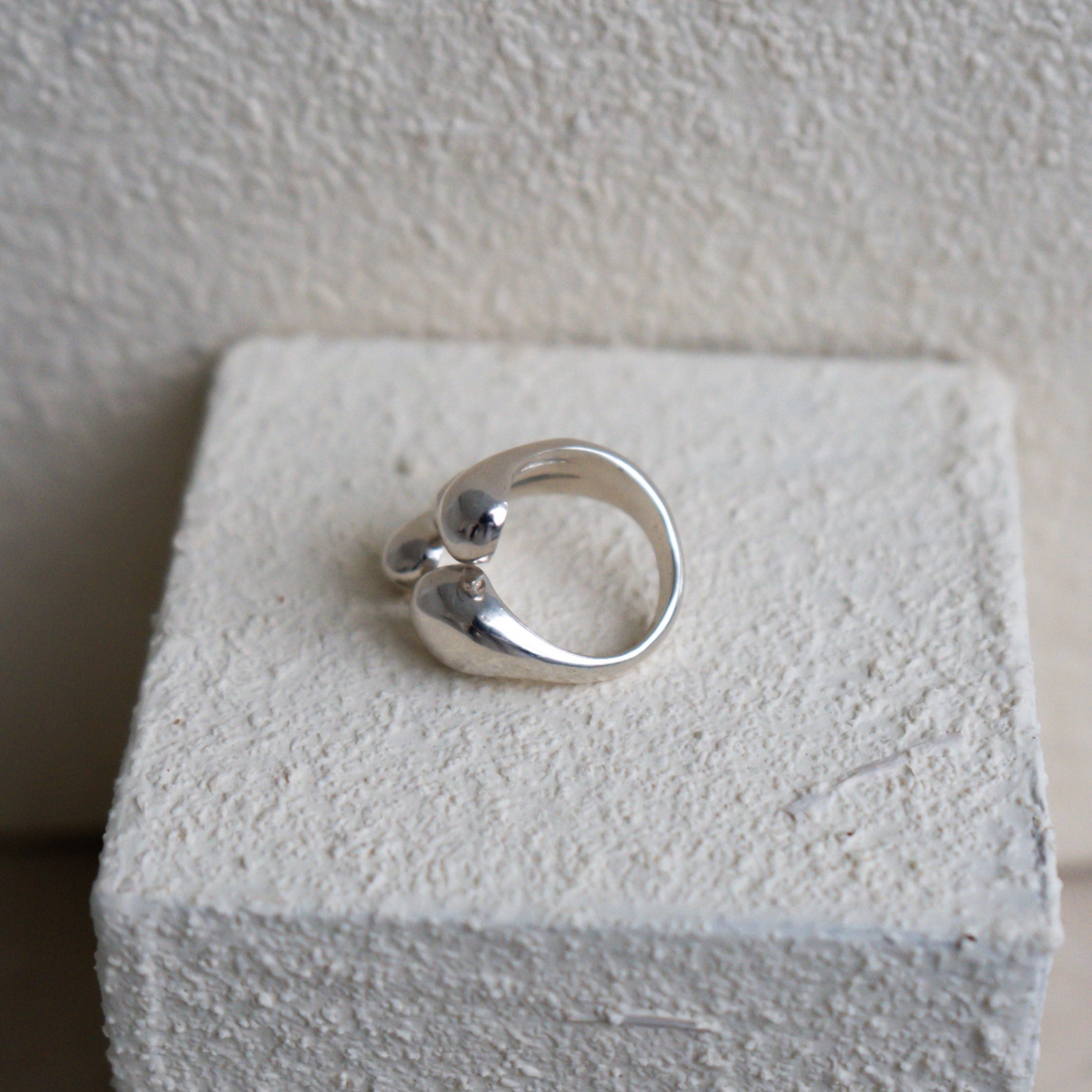 Silver ring on a white cube with a plain background