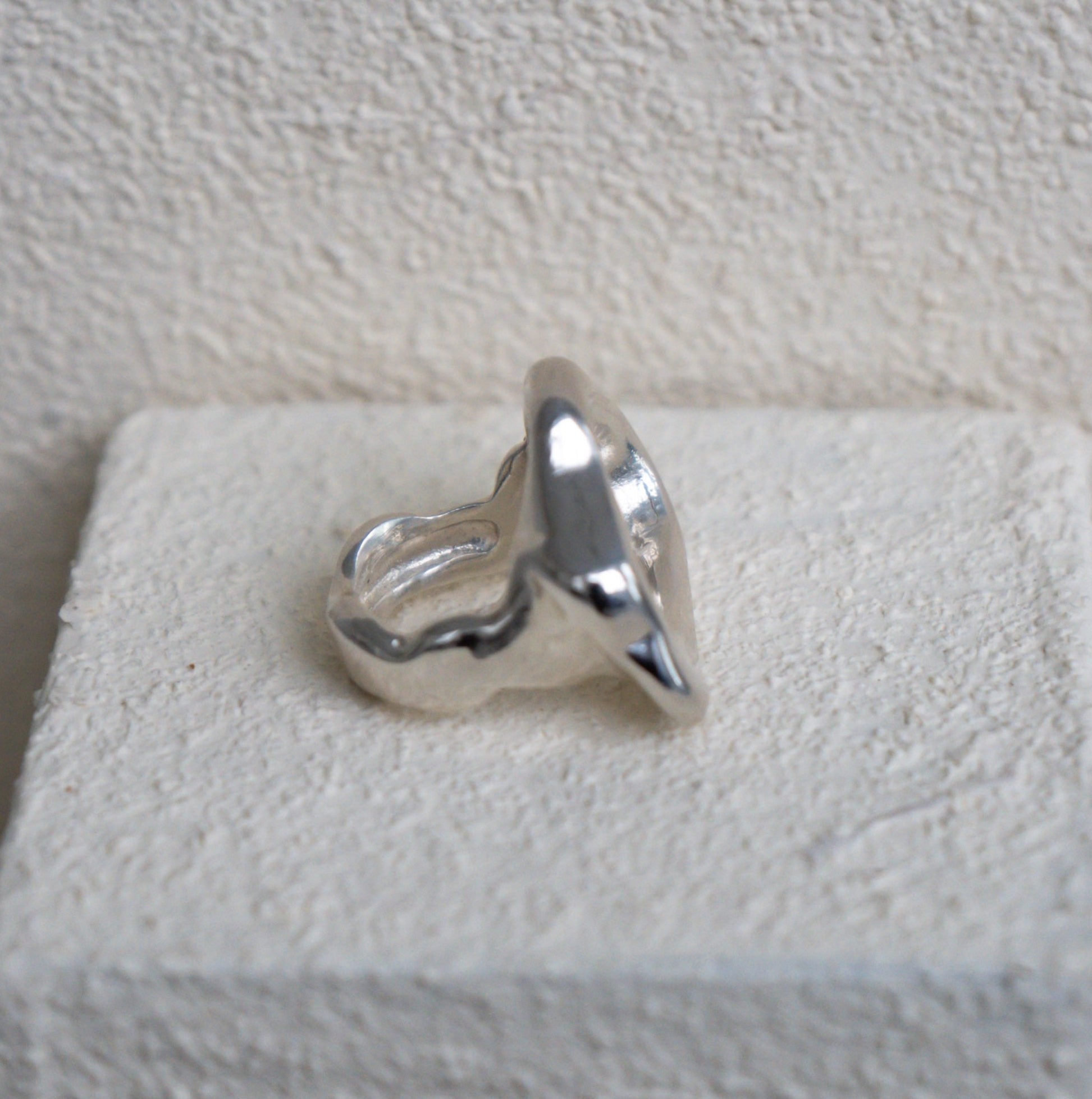 Wavy Silver ring on a textured white block against a light gray background